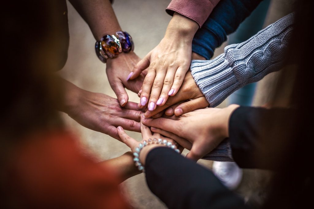 Groupe de personnes posant leurs mains les unes sur les autres en signe d’unité, de solidarité et de travail d’équipe.